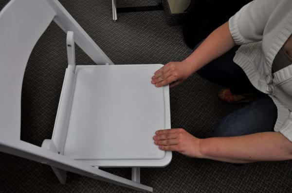 Snapping Seat into Place on White Resin Folding Chair