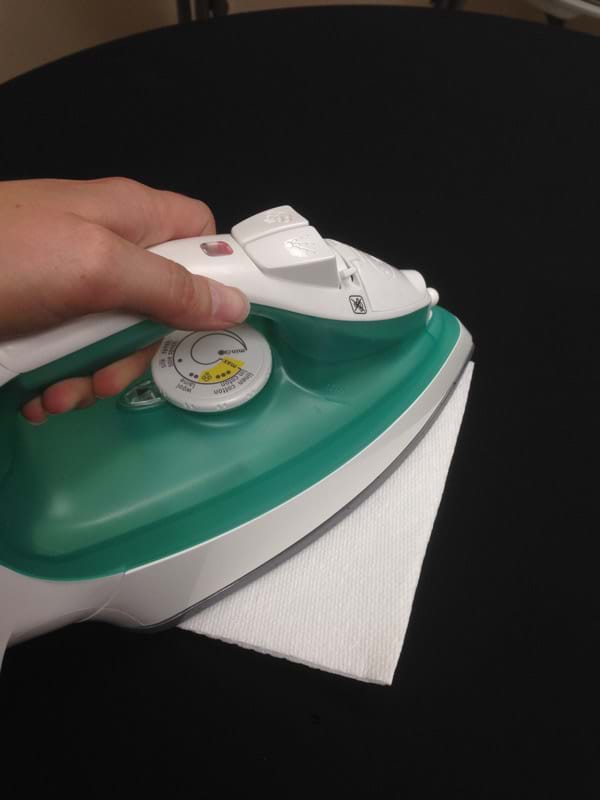 Iron on Top of Paper Towel to get Wax Off